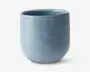 En glat, cylindrisk kop med mat blå finish. Koppen har en let afrundet bund og en tynd kant uden hank. Overfladen er jævn, og farven er ensartet, hvilket giver et moderne og minimalistisk udtryk.